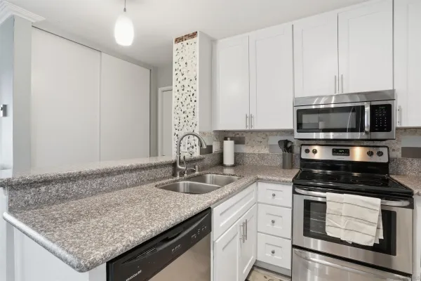 a kitchen with granite countertop a sink stainless steel appliances and white cabinets