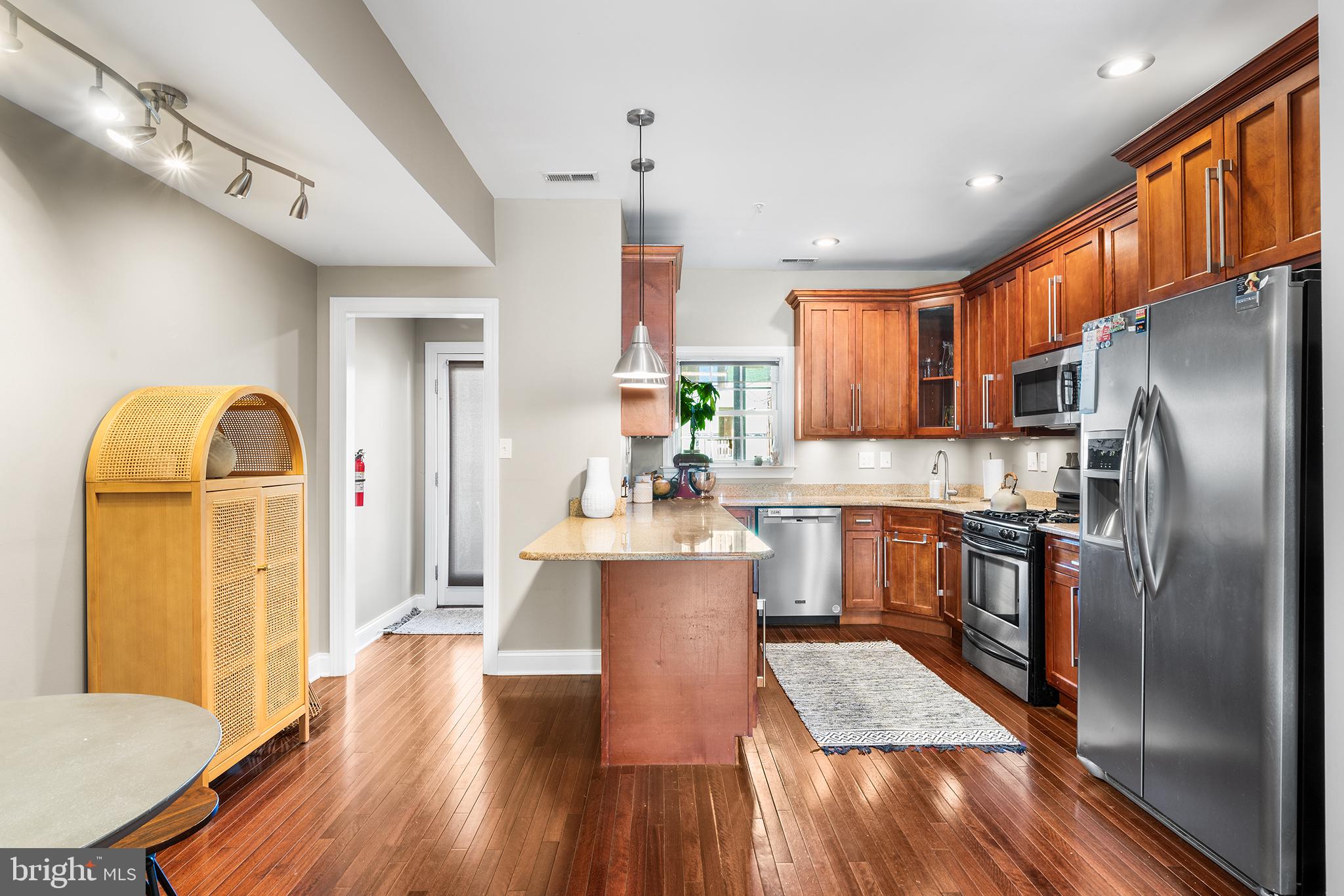 1927 Poplar Street, Unit B Philadelphia, PA 19130 - Photo 7 of 27 a kitchen with stainless steel appliances granite countertop a refrigerator a stove top oven a chimney cabinets and wooden floor