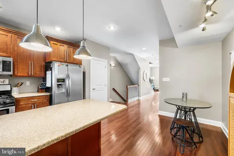 a kitchen with stainless steel appliances refrigerator wooden floor dining table and chairs
