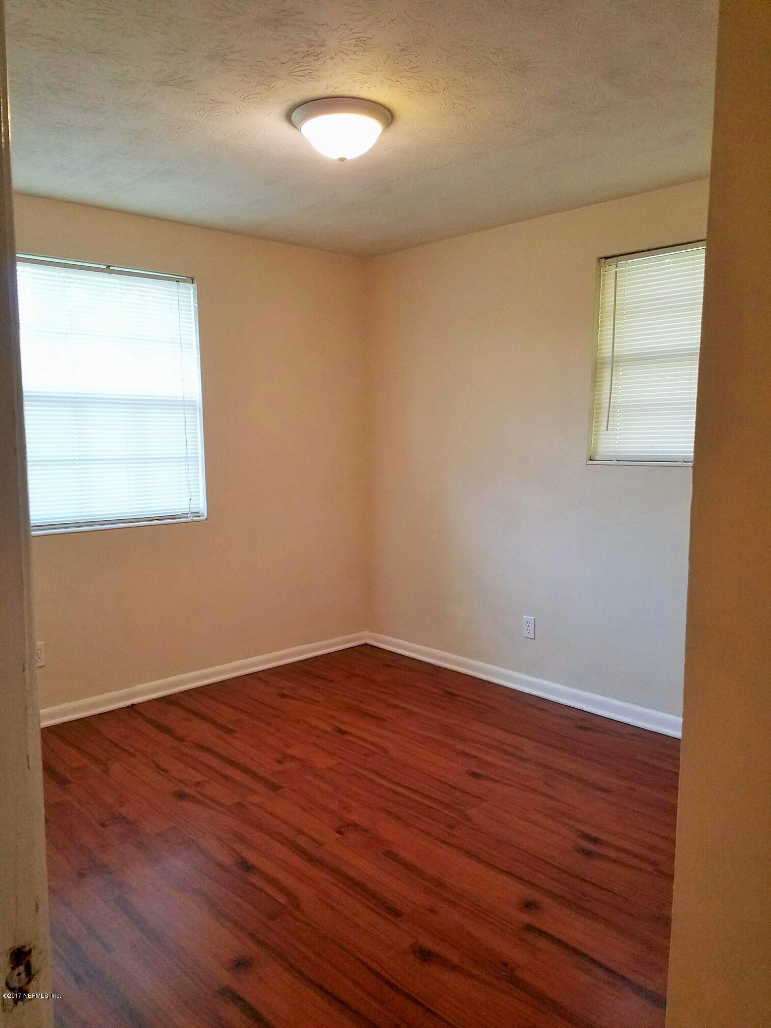6556 Todd Road Jacksonville, FL 32216 - Photo 9 of 17 an empty room with wooden floor and windows