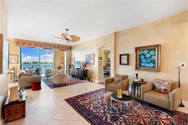 a living room with furniture large windows a rug and a view of kitchen