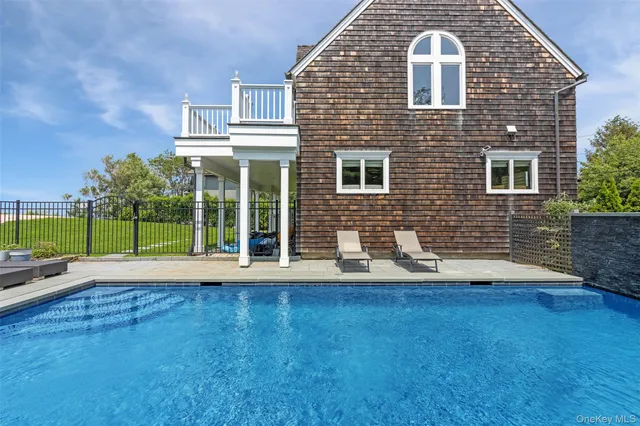 a view of swimming pool with lawn chairs and iron fence