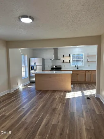 a living room with stainless steel appliances granite countertop a dishwasher and a stove with wooden floor