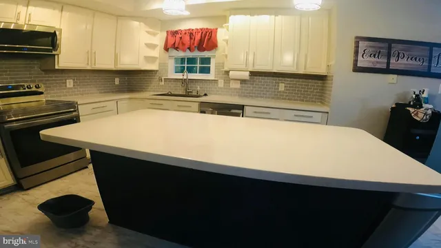 a kitchen with stainless steel appliances a sink dishwasher a stove a dining table and chairs with wooden floor