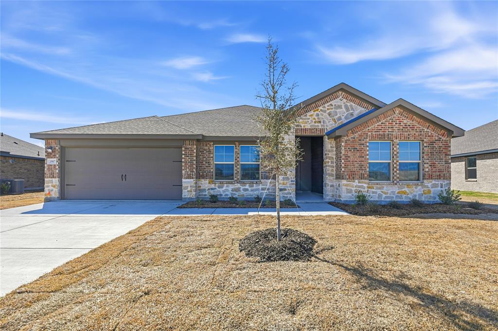 1907 Reveille Way Terrell, TX 75160 - Photo 1 of 6 Single-story residence featuring a brick and stone facade, an attached two-car garage, multiple front-facing windows, and a concrete driveway