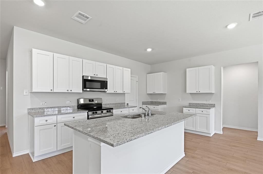 1907 Reveille Way Terrell, TX 75160 - Photo 3 of 6 Modern kitchen featuring a central island, white shaker cabinetry, stainless steel appliances, recessed lighting, and wood-finish flooring