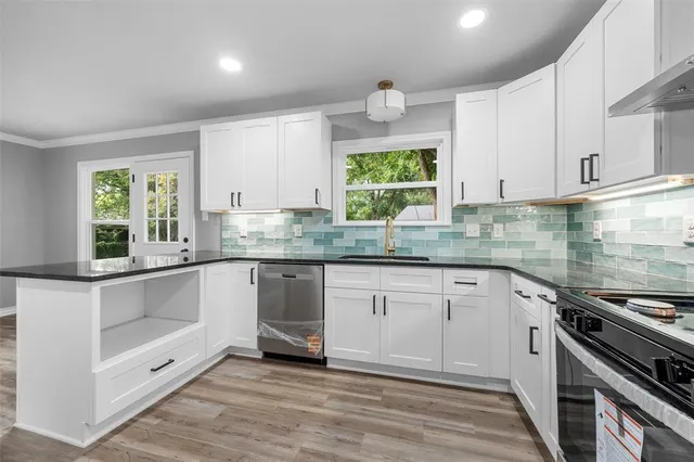 a kitchen with stainless steel appliances granite countertop a stove a sink and a white cabinets