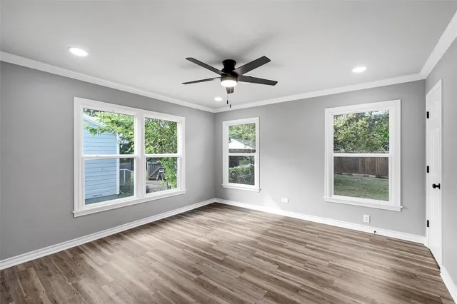 a view of an empty room with a window and wooden floor
