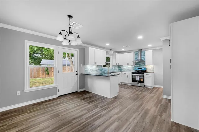 a kitchen with stainless steel appliances granite countertop a refrigerator a sink dishwasher a stove and white countertops with wooden floor