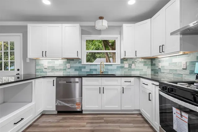 a kitchen with stainless steel appliances granite countertop a sink stove and cabinets