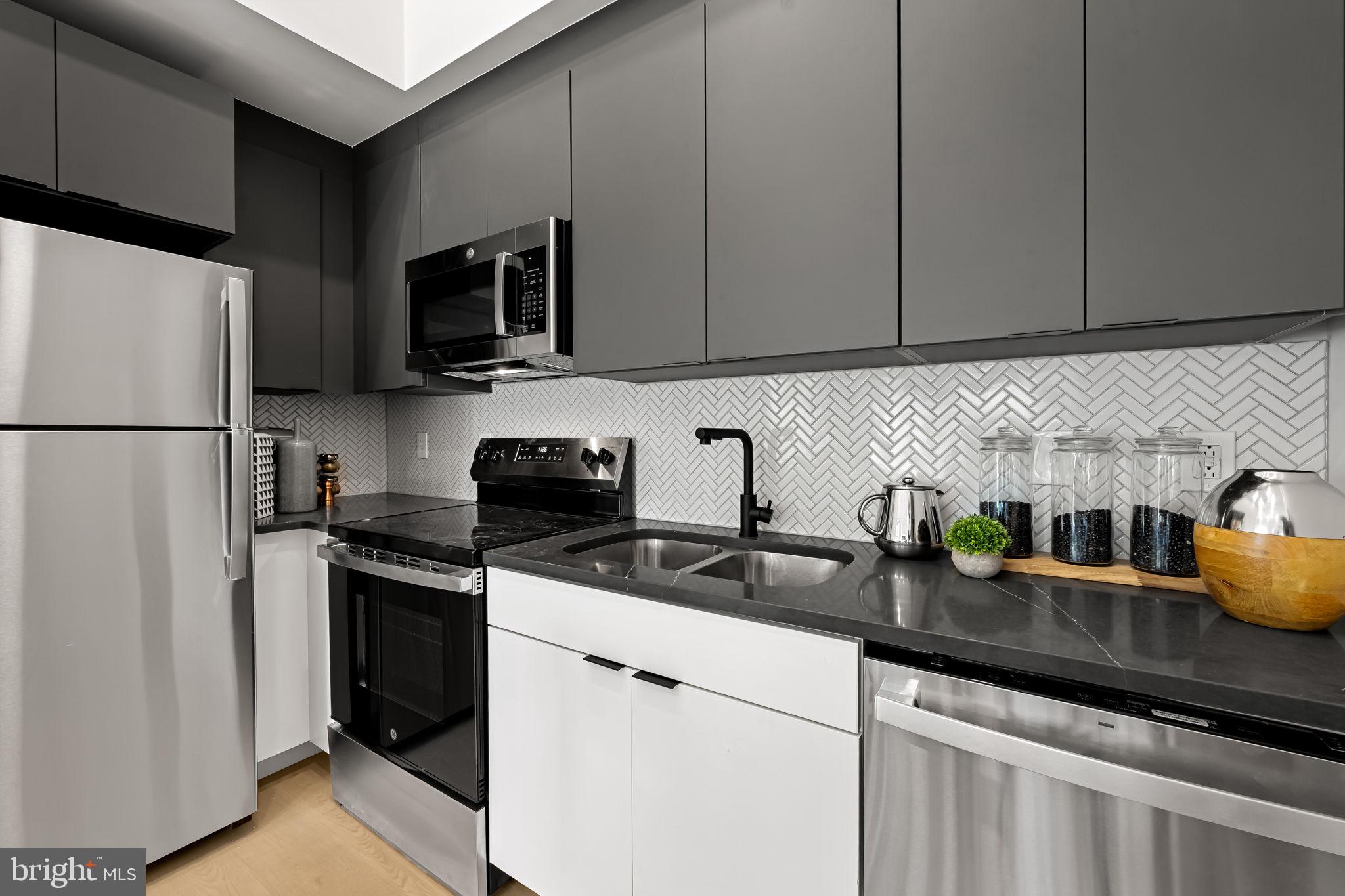 600 North Howard Street, Unit 103 Baltimore, MD 21201 - Photo 7 of 20 a kitchen with stainless steel appliances granite countertop a refrigerator a sink a stove a microwave and cabinets