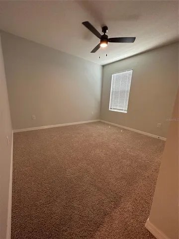 an empty room with a ceiling fan and a window