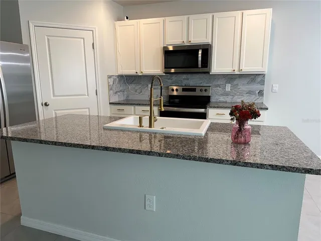 a kitchen with granite countertop a sink a stove and microwave