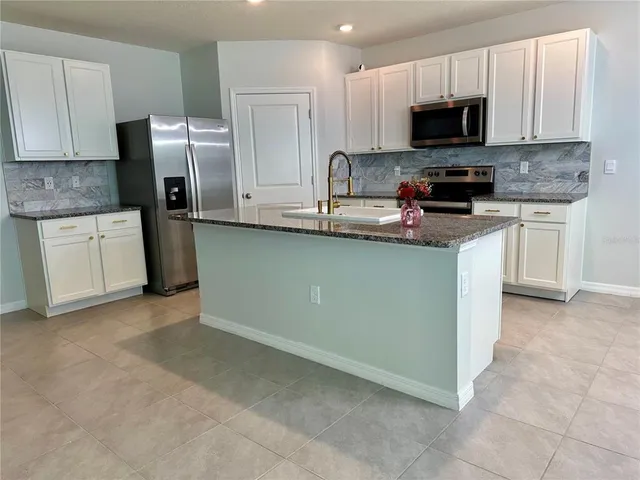 a kitchen with stainless steel appliances granite countertop a stove a sink a microwave a refrigerator and cabinets