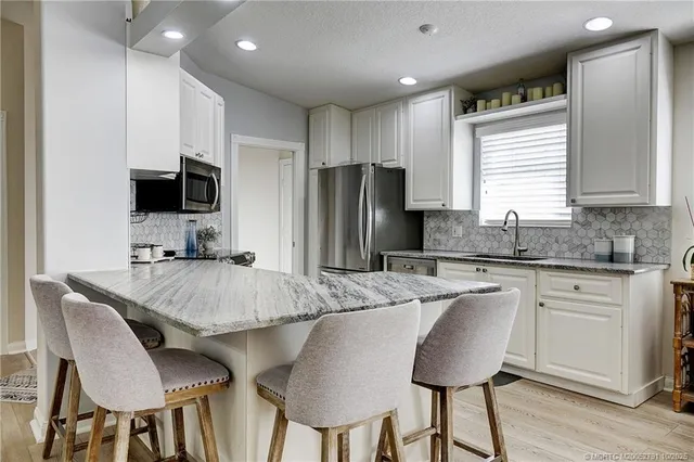 a large white kitchen with a large window and stainless steel appliances