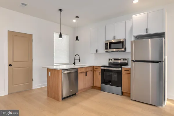 a kitchen with stainless steel appliances granite countertop a refrigerator a stove a sink and a microwave