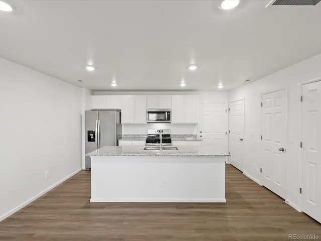 a large white kitchen with wooden floor and a sink