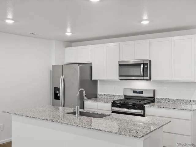a kitchen with stainless steel appliances granite countertop a stove a sink and a microwave