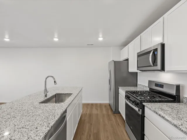 a kitchen with stainless steel appliances granite countertop a sink stove and refrigerator