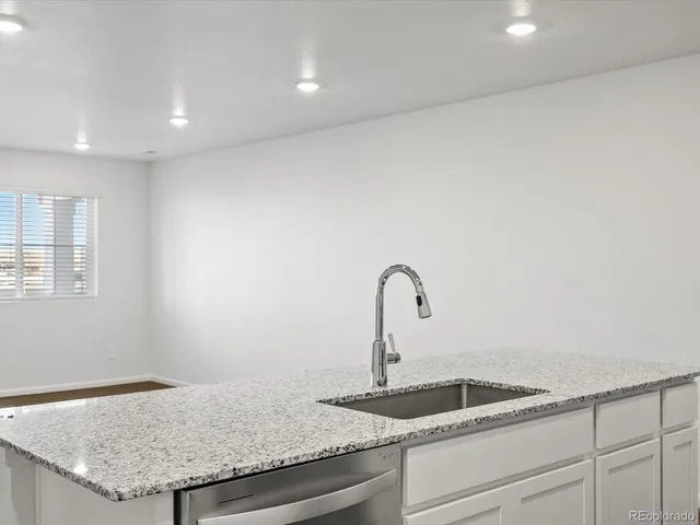 a kitchen with granite countertop a sink and white cabinets