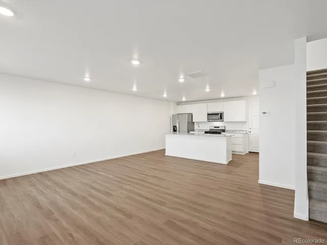 a view of kitchen with kitchen island a sink wooden floor and a refrigerator