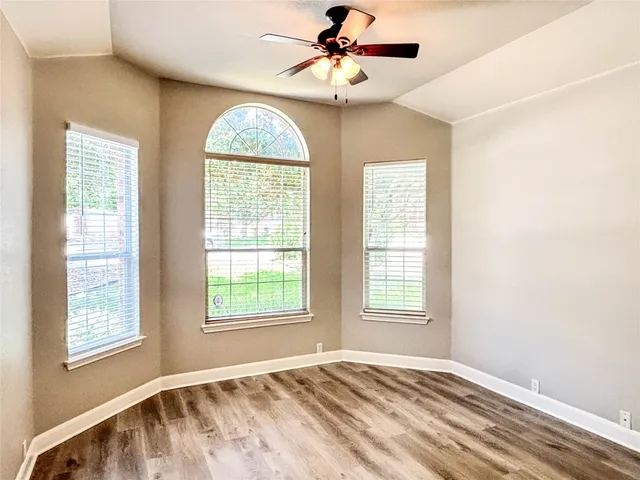 a view of an empty room with chandelier fan and a window