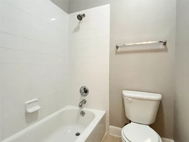 a white toilet sitting next to a white bath tub