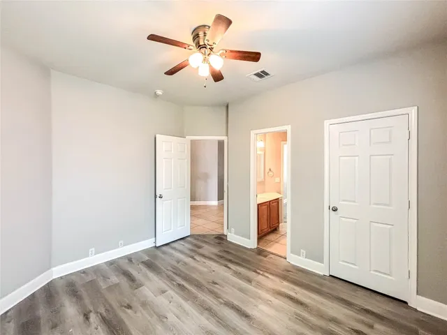 an empty room with wooden floor and ceiling fan