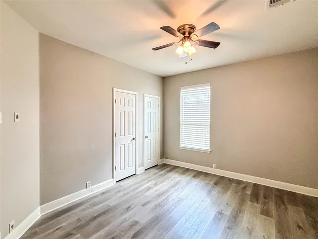 an empty room with wooden floor and chandelier fan