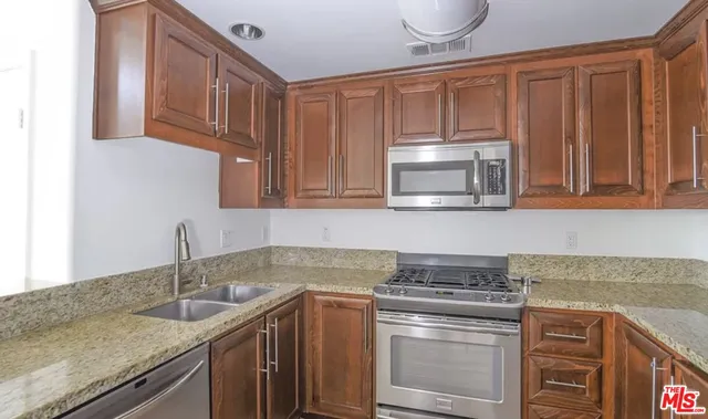 a kitchen with granite countertop a sink stove and cabinets