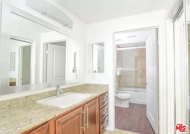 a bathroom with a granite countertop sink toilet and shower