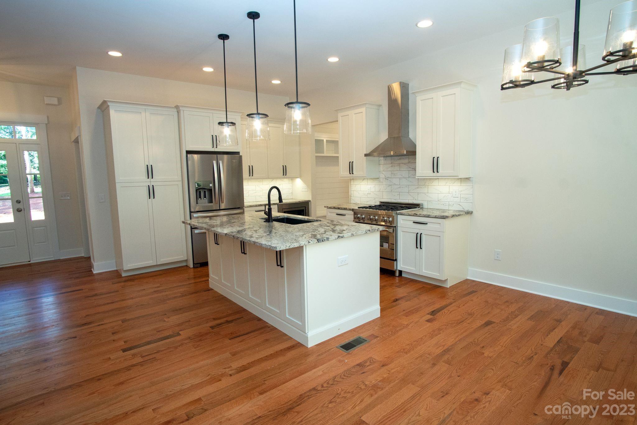 1495 Golf Course Road Columbus, NC 28722 - Photo 16 of 47 a kitchen with stainless steel appliances granite countertop a sink a stove a refrigerator and a wooden floor