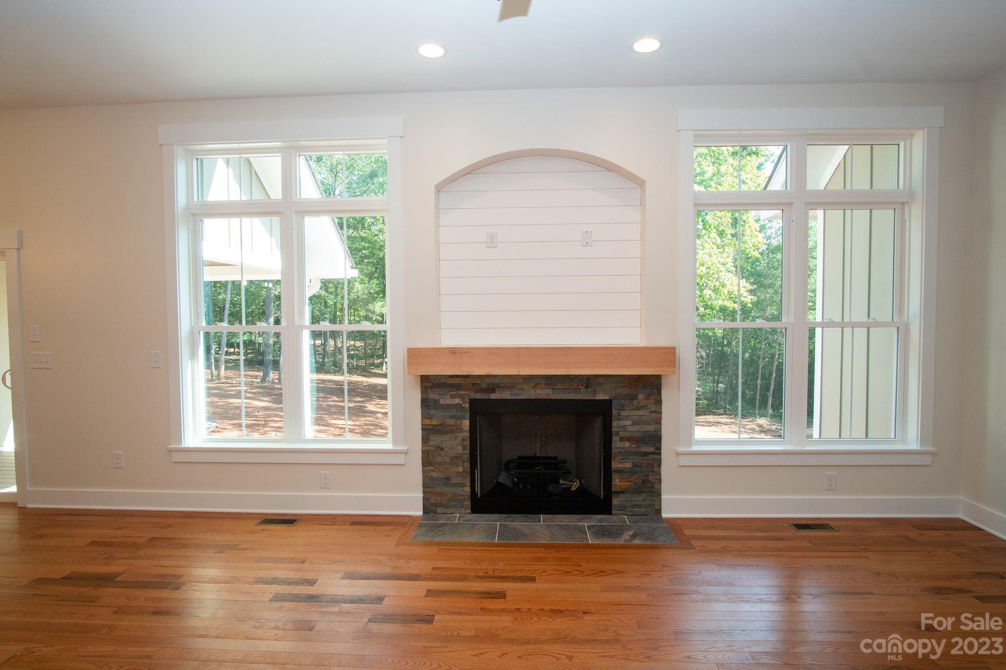 1495 Golf Course Road Columbus, NC 28722 - Photo 19 of 47 an empty room with wooden floor fireplace and windows