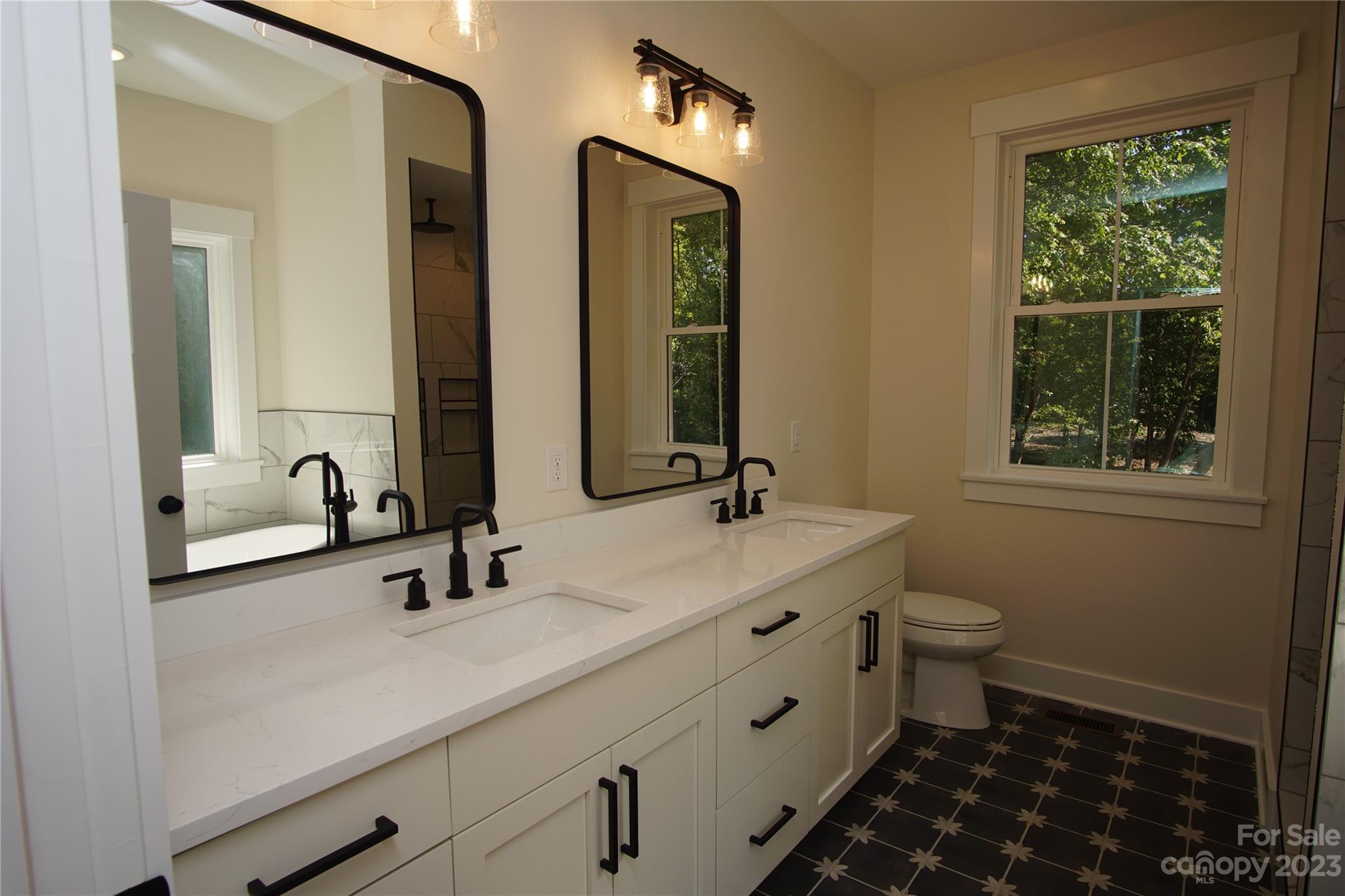 1495 Golf Course Road Columbus, NC 28722 - Photo 33 of 47 a bathroom with double vanity sinks a toilet and a mirror