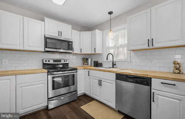 a kitchen with cabinets stainless steel appliances a sink and a window