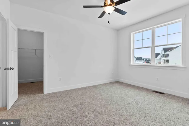 an empty room with a window and a ceiling fan