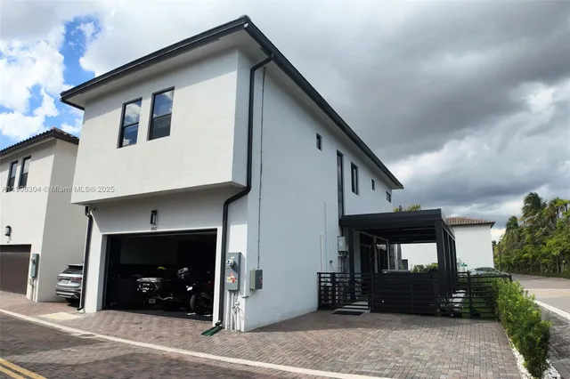 a view of a white house with large windows and a yard