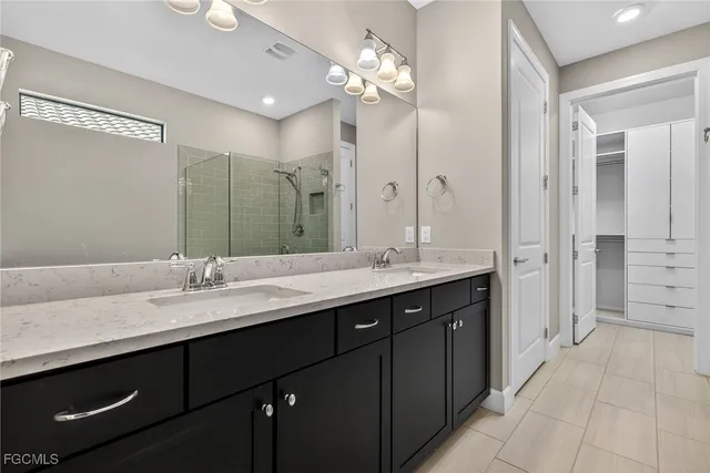 a bathroom with a sink double vanity granite tub shower and a mirror