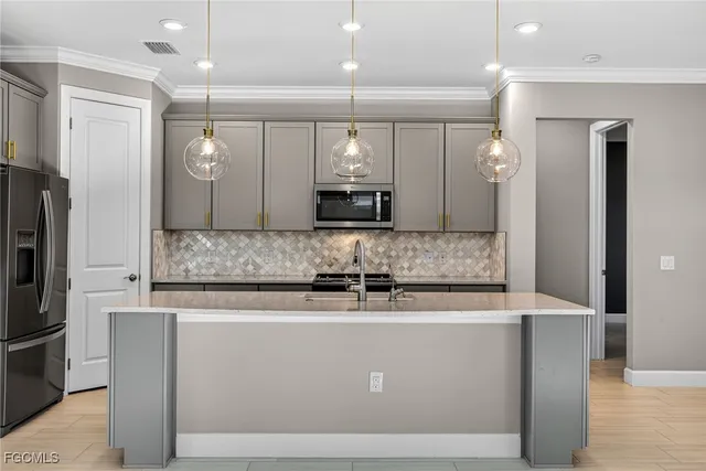 a view of a counter top space a sink a refrigerator and a window