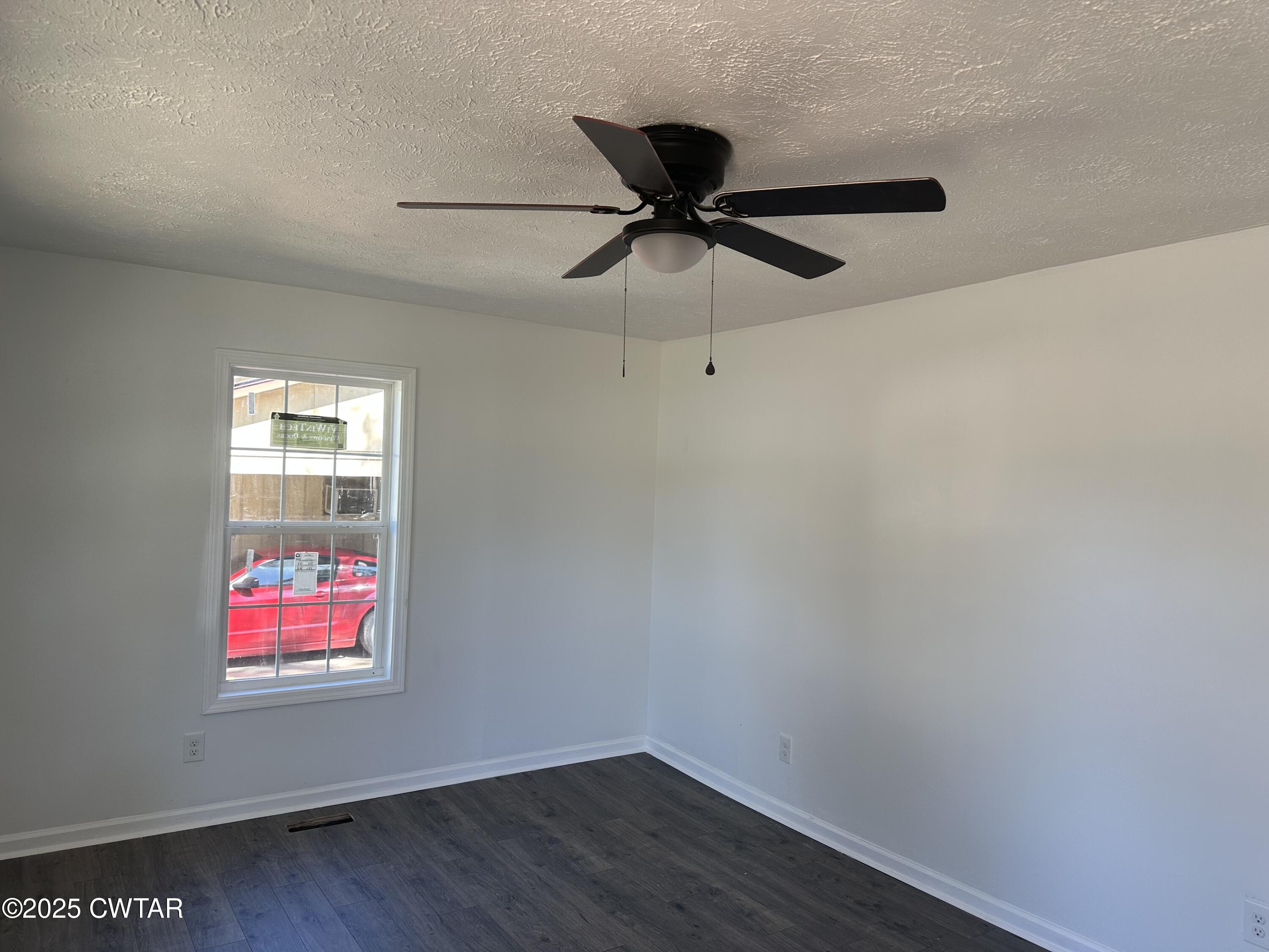 328 Baughn Street Henderson, TN 38340 - Photo 7 of 16 an empty room with wooden floor fan and windows