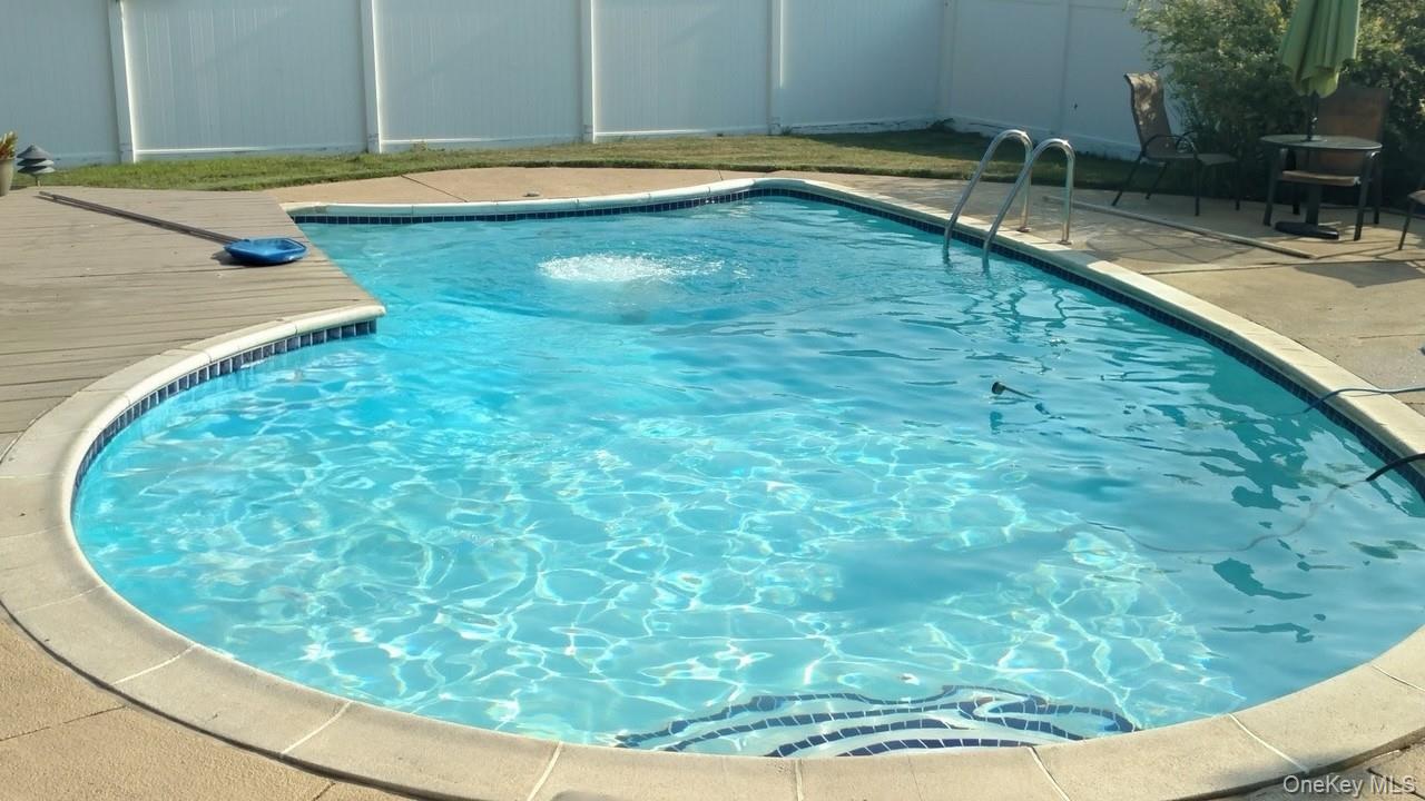 212 Matthews Road Oakdale, NY 11769 - Photo 4 of 7 In-ground swimming pool, salt water, featuring a curved design, concrete coping, and mosaic tile accents