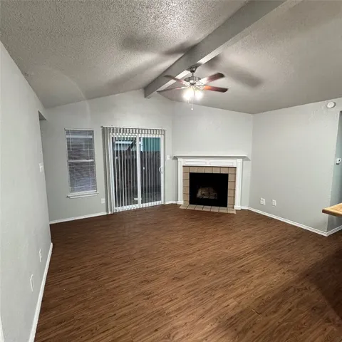 a view of an empty room with wooden floor fireplace and a window