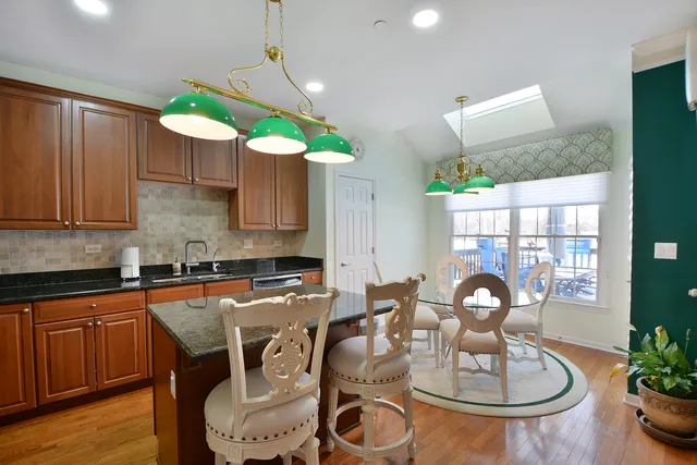 a kitchen with granite countertop a table chairs stove and wooden floor