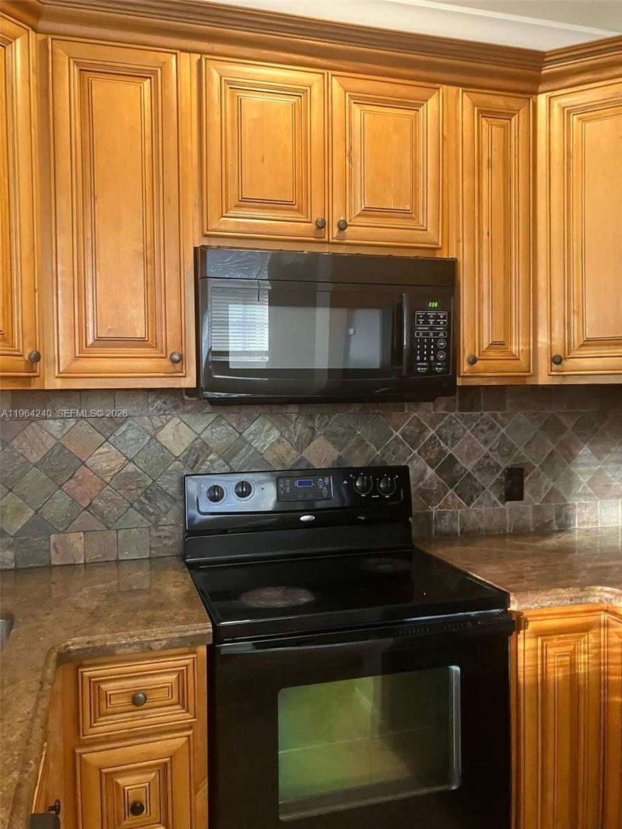 620 Cypress Club Way, Unit L13 Deerfield Beach, FL 33064 - Photo 5 of 14 a kitchen with granite countertop wood cabinets and a stove top oven