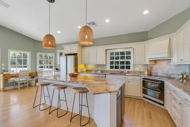 a kitchen with stainless steel appliances granite countertop a stove a sink dishwasher a dining table and chairs with wooden floor