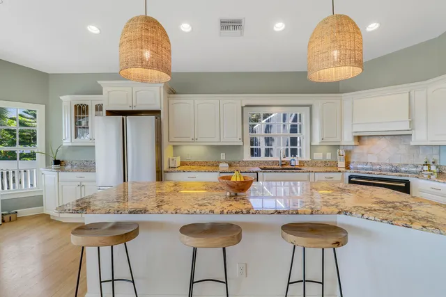 a kitchen with granite countertop a stove a sink dishwasher a dining table and chairs with wooden floor