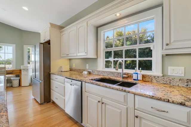 a kitchen with granite countertop a sink and white cabinets