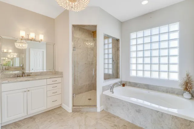 a spacious bathroom with a granite countertop tub sink shower and two mirror