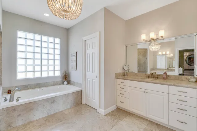 a spacious bathroom with a granite countertop sink a mirror a bathtub and next to a window