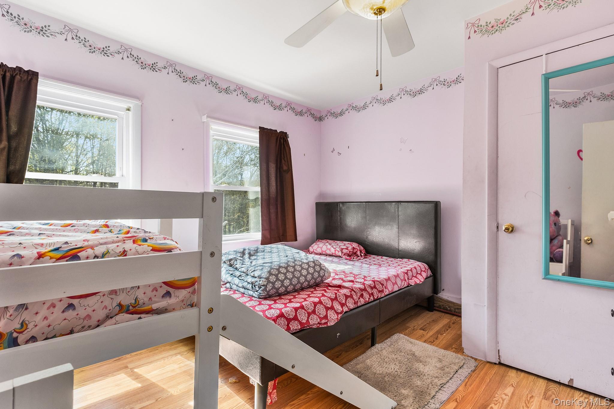 43 Taylor Road Parksville, NY 12768 - Photo 18 of 29 Light-filled room featuring two windows with white trim, wood-finish flooring, and a ceiling fan with integrated lighting